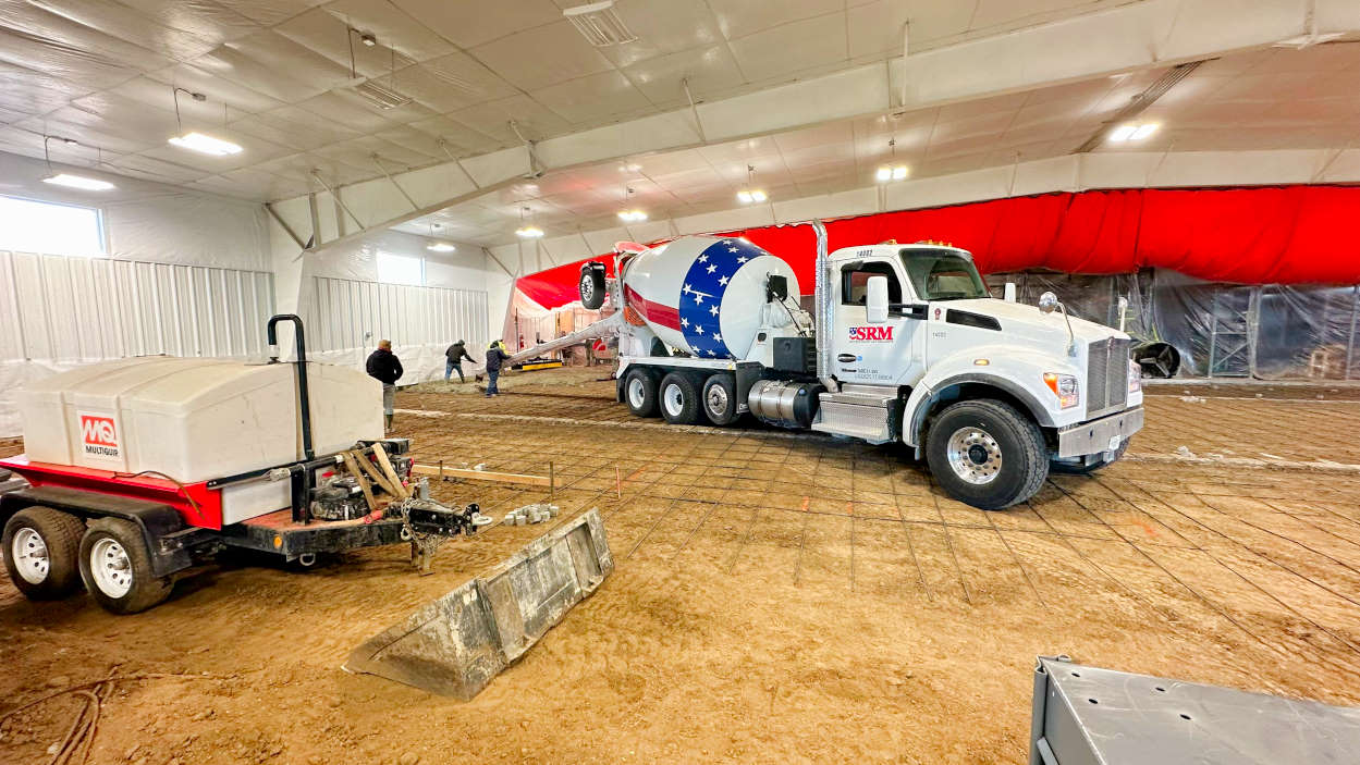 A concrete truck pours fresh concrete in the new addition to the BAS Aircraft Salvage hangar in Greeley, CO